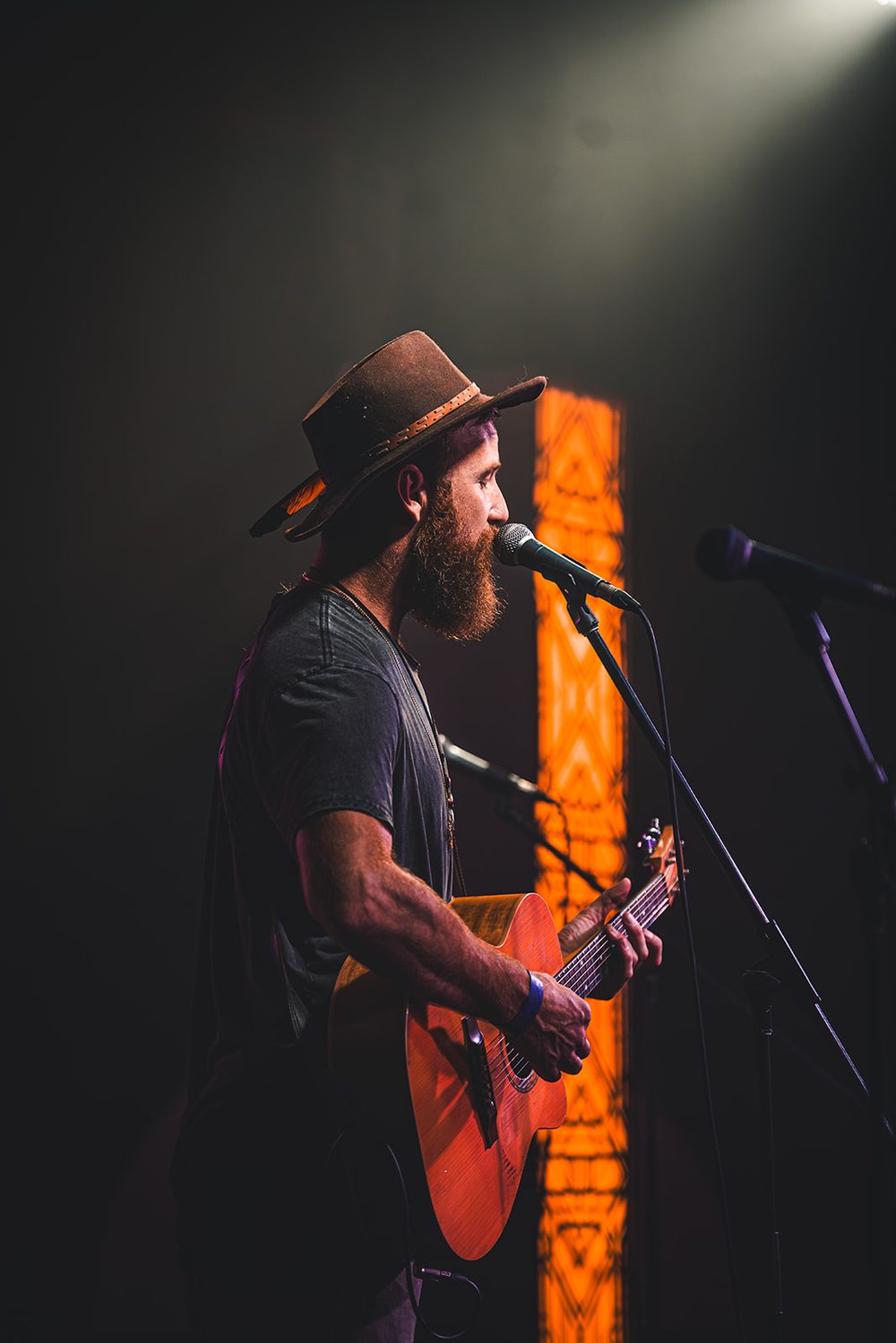 At the microphone, bathed in orange light